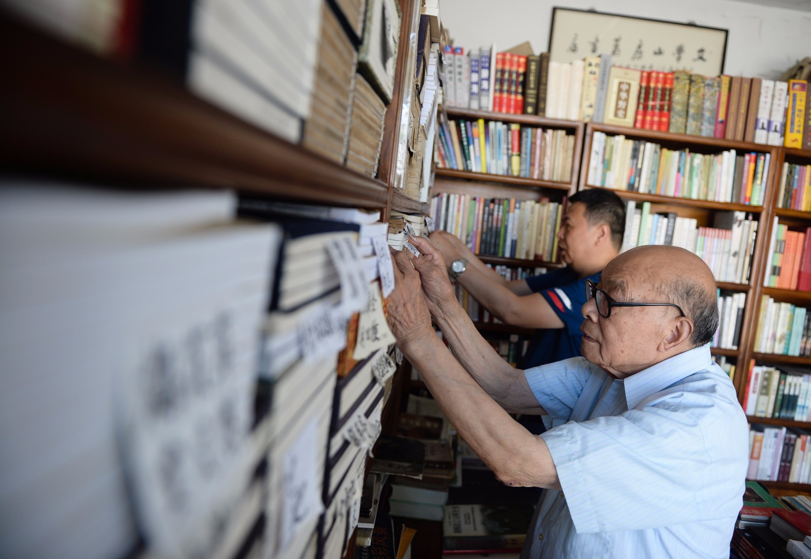    7月18日，在“文学山房”旧书店，江澄波老人和前来书店陪伴他的儿子江益林一起整理书籍。
