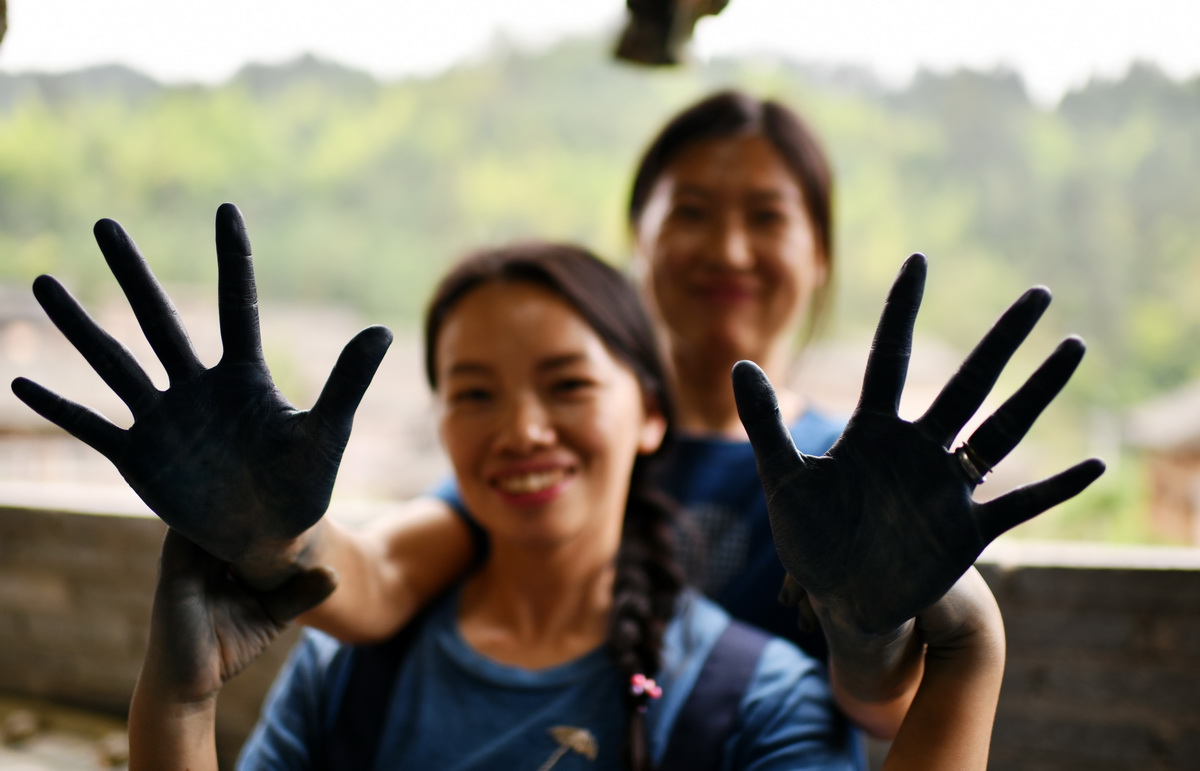 杨成兰（前）与一名学徒在展示被植物染料染黑的双手（5月28日摄）。